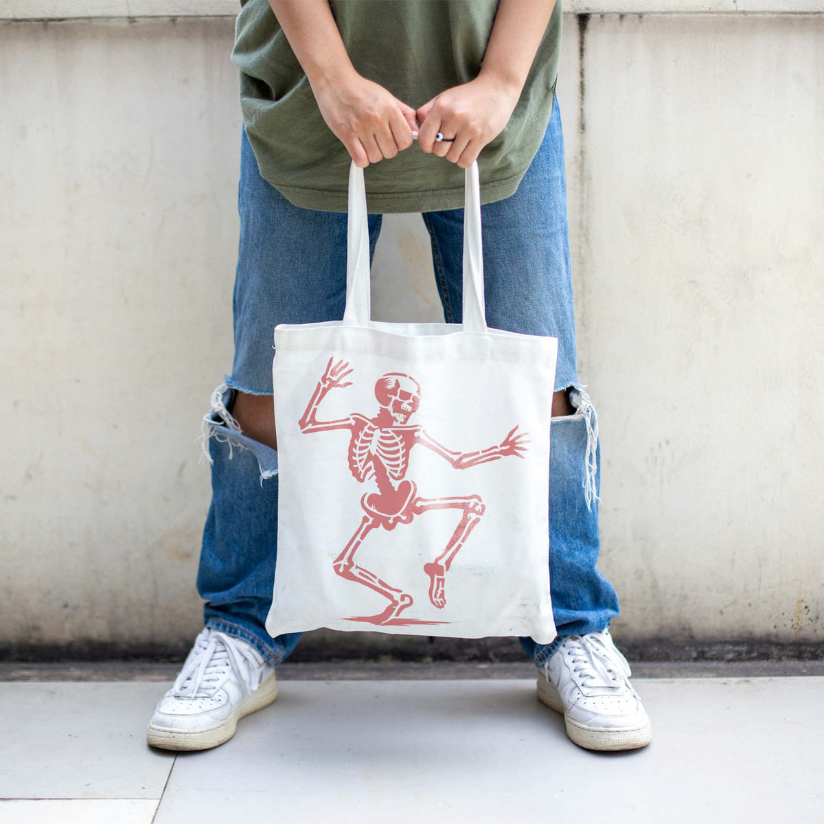A Dancing Skeleton Halloween Stencil decorates a white tote bag with a playful coral figure