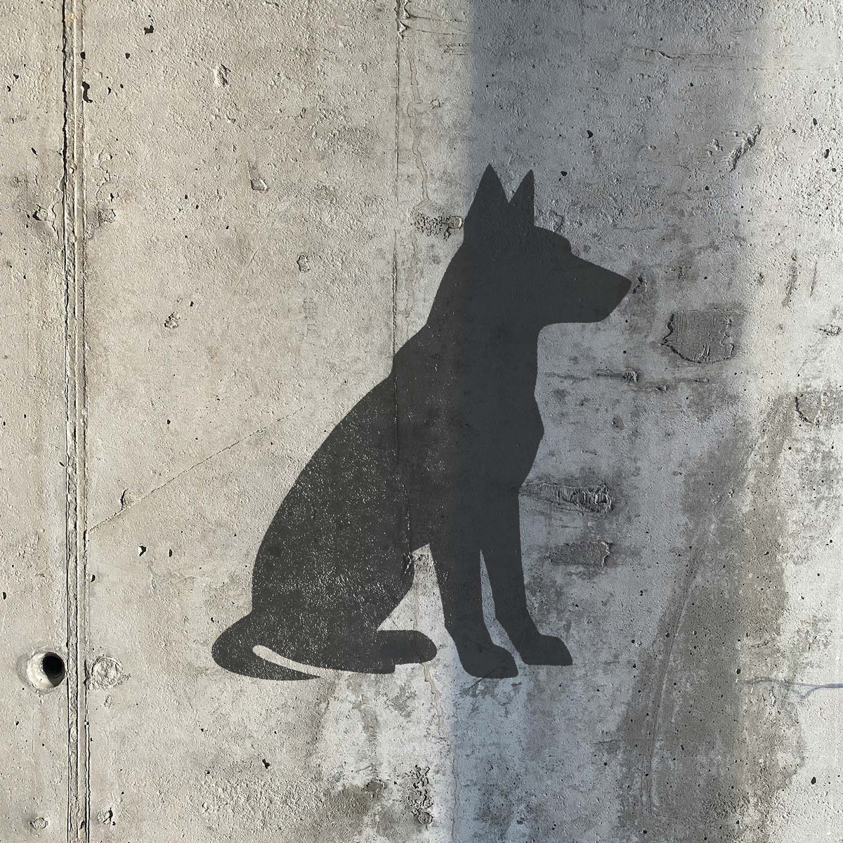 Sitting Dog Silhouette Stencil forms a bold black canine profile on weathered concrete