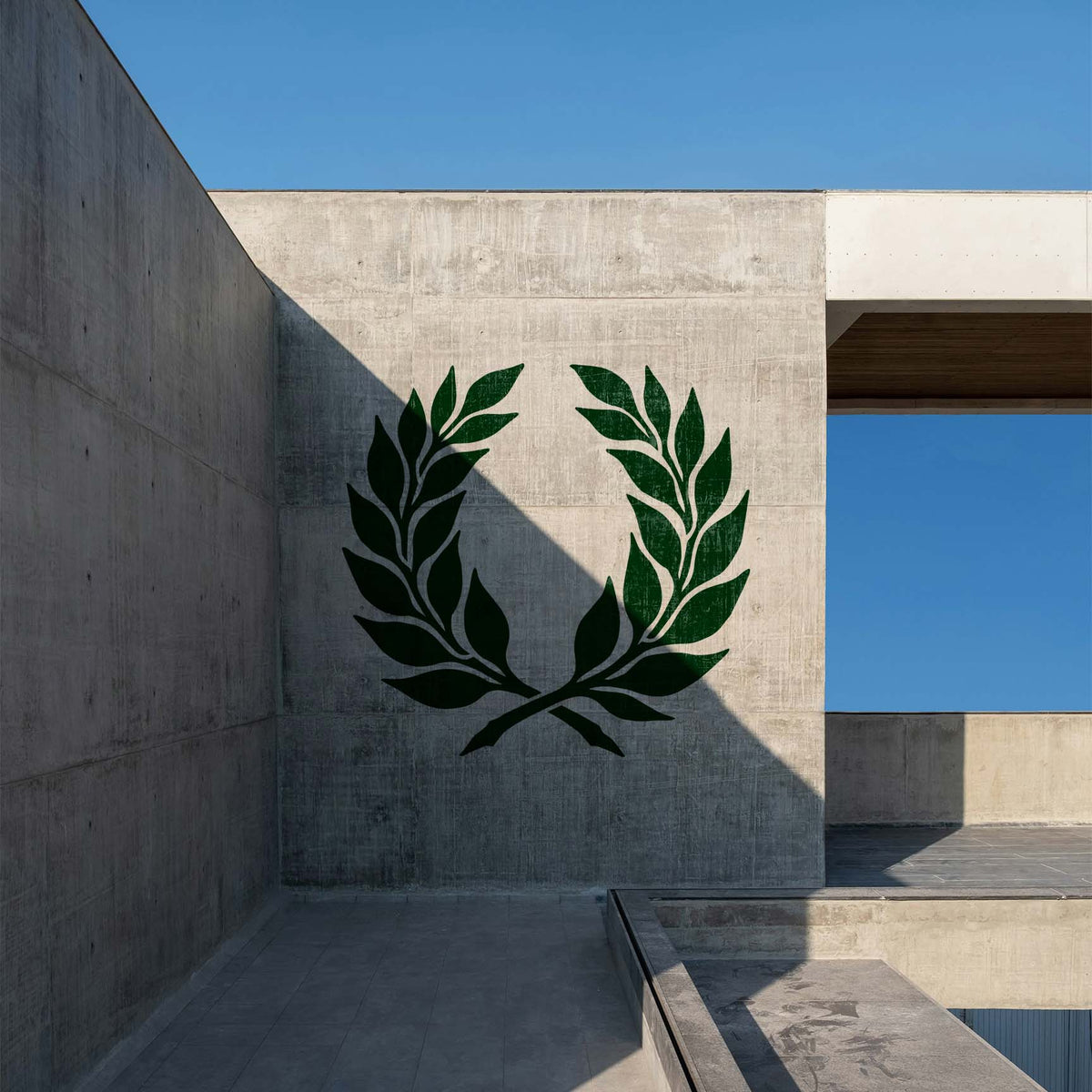 Elegant Laurel Wreath Stencil painted in deep green on a concrete wall in a modern outdoor space.