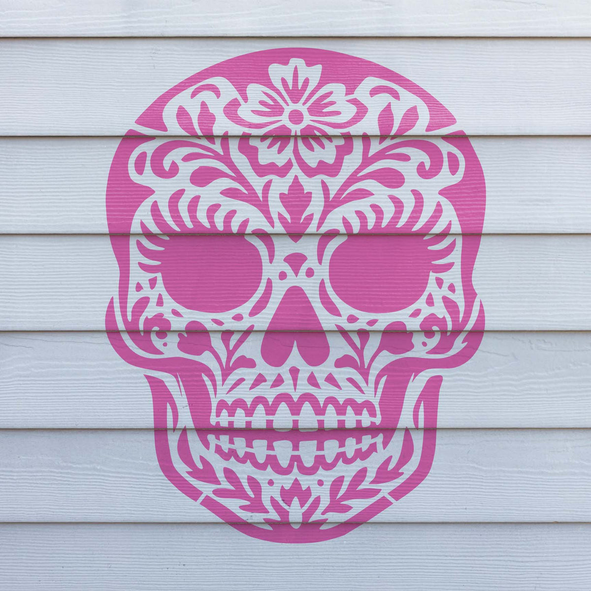 Floral details shape the pink Female Sugar Skull Stencil painted on white exterior siding