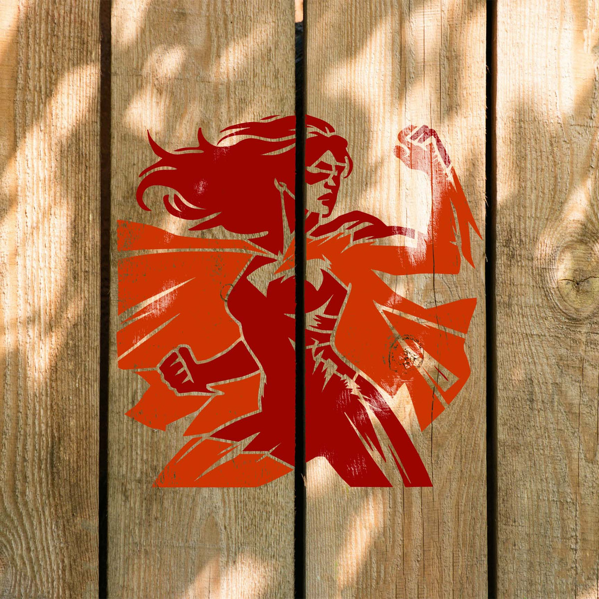 Sunlit wood displays the Empowered Female Superhero Stencil with raised fist and flowing cape