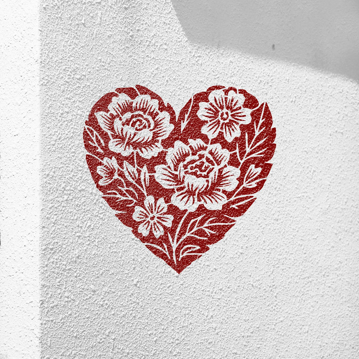 Floral Heart Bouquet Stencil painted in red on a textured white stucco wall.