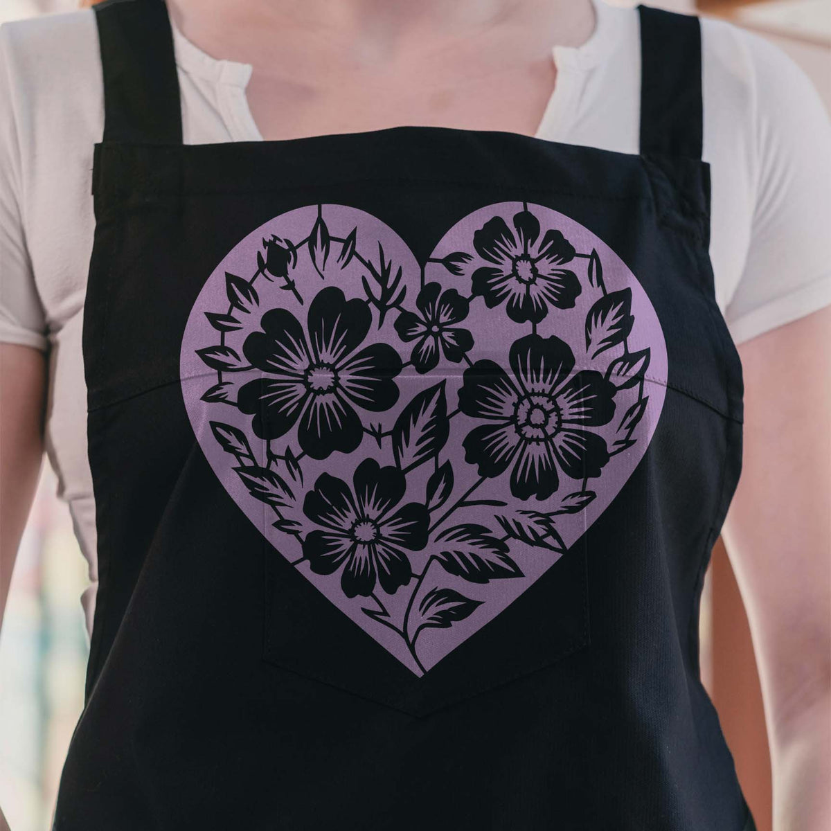 Floral Heart Silhouette Stencil blooms in soft purple across a black apron with leafy flower details