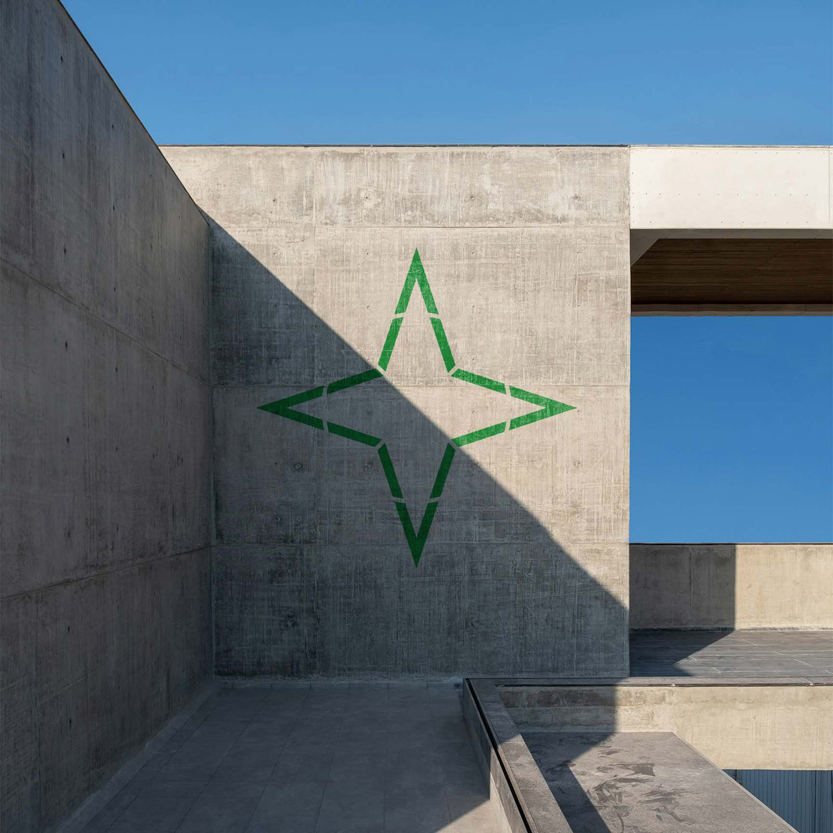 Four Point Star Outline Stencil appears in green across a sunlit modern concrete wall