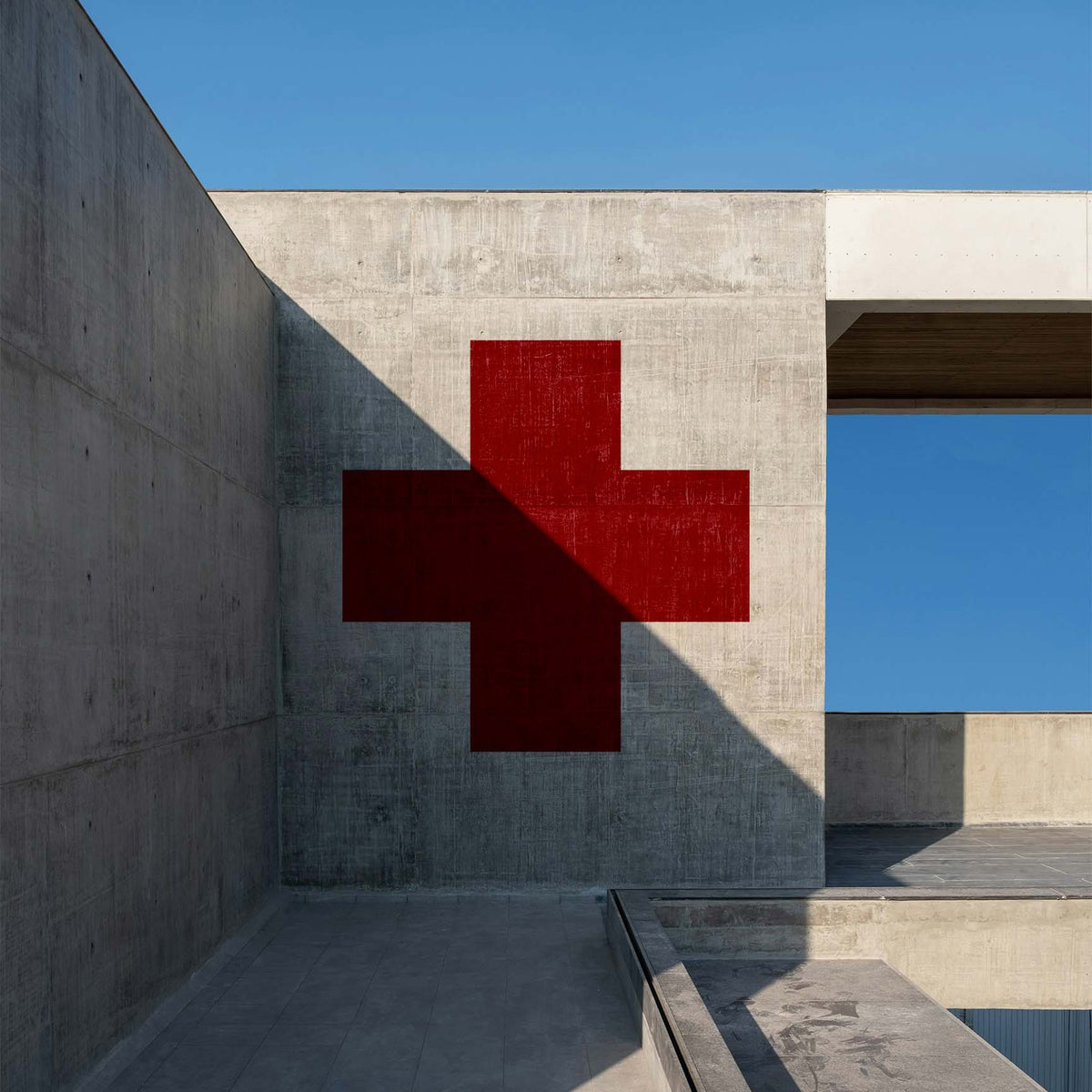 Bold Greek Cross Stencil painted red across a modern gray concrete wall