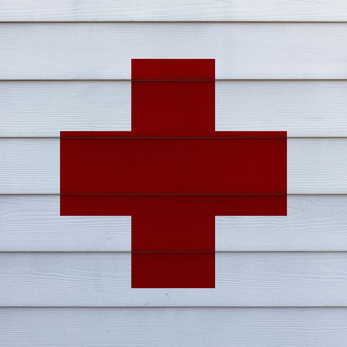 Large red Greek Cross Stencil displayed across clean white horizontal wall siding