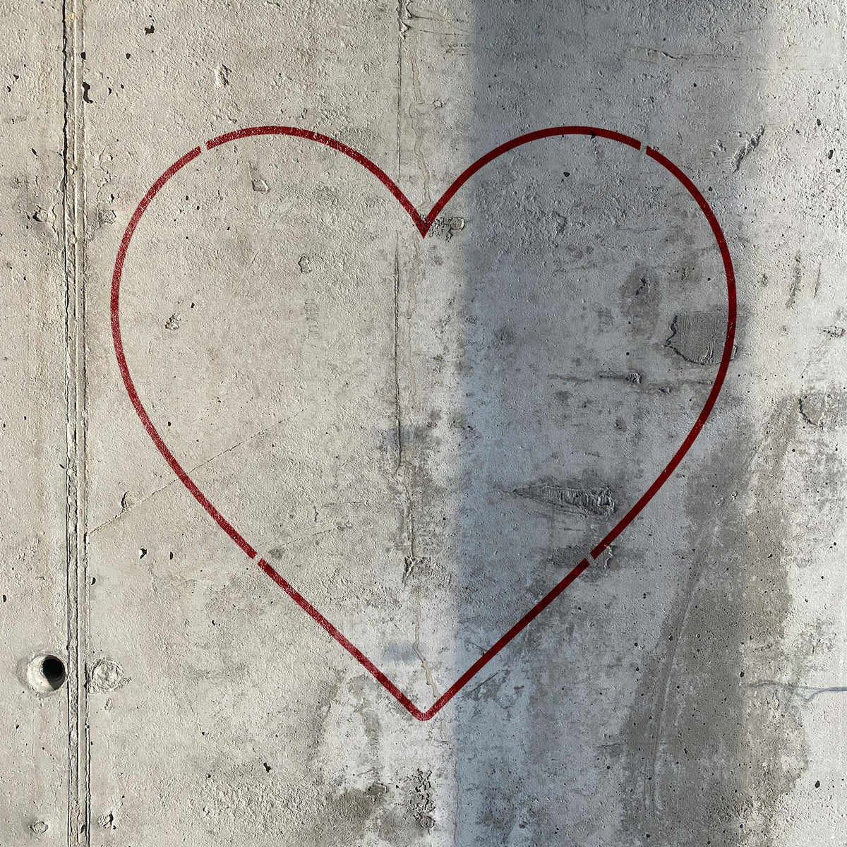 Heart Outline Stencil traces a simple red heart across a raw concrete wall with natural texture