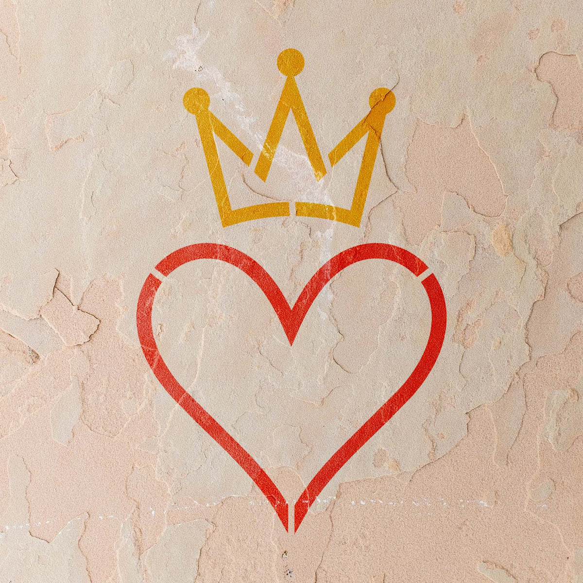On a weathered stucco wall, the Crowned Heart Outline Stencil pairs a red heart with a gold crown