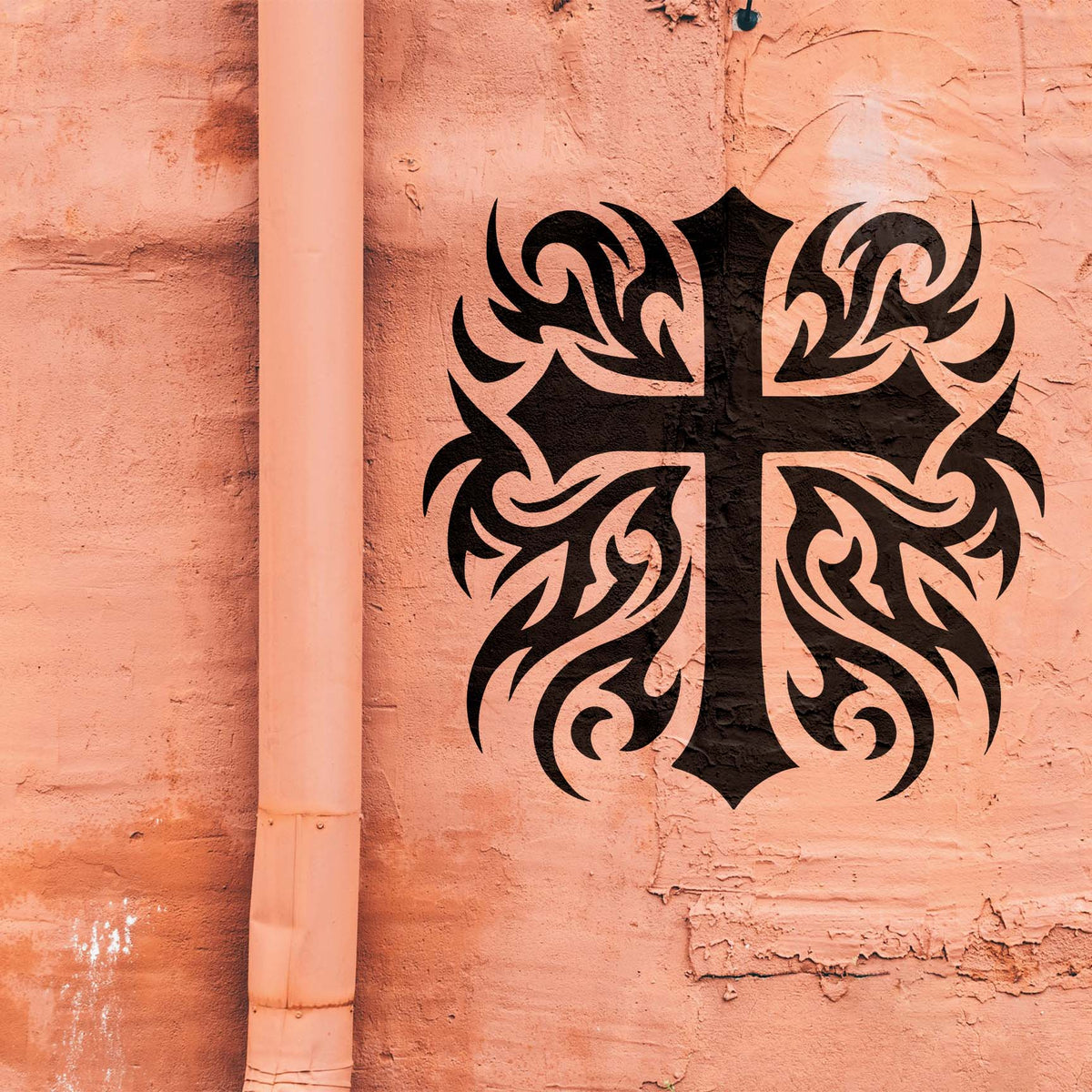 Heritage Tribal Cross Stencil displayed in black on a textured peach wall mural.