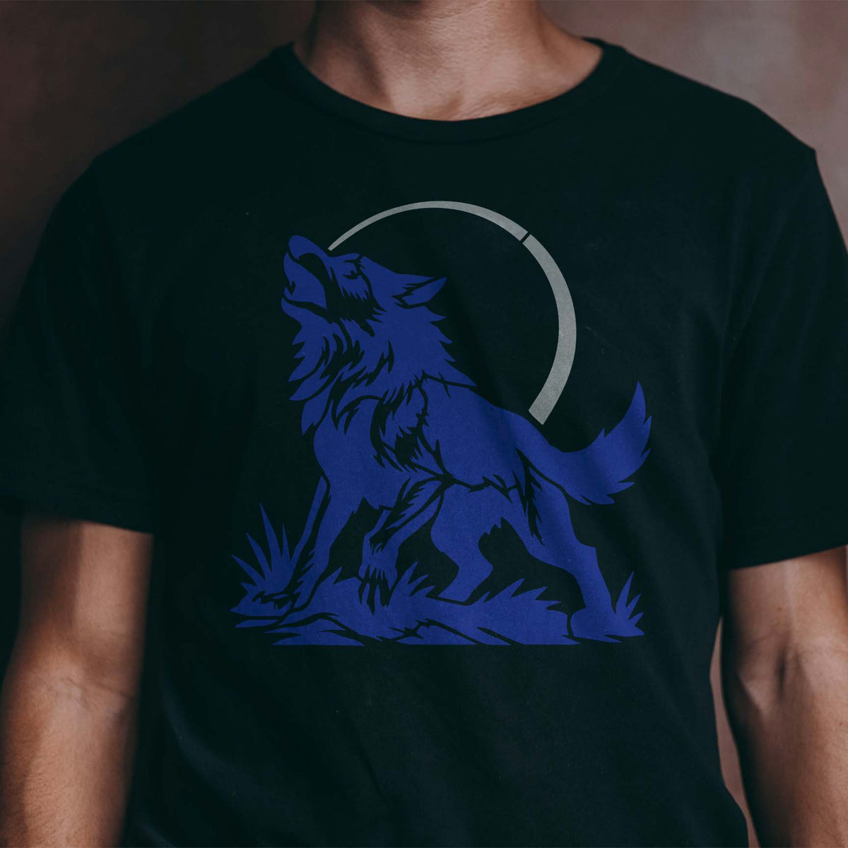 A silver Howling Wolf Under Moon Stencil captures a wild wolf howling beneath the moon on a black t-shirt.