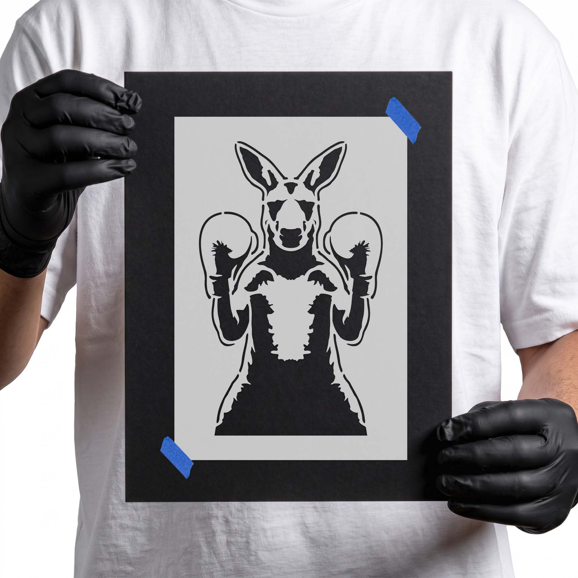 Person holding Boxing Kangaroo Stencil taped to black cardboard