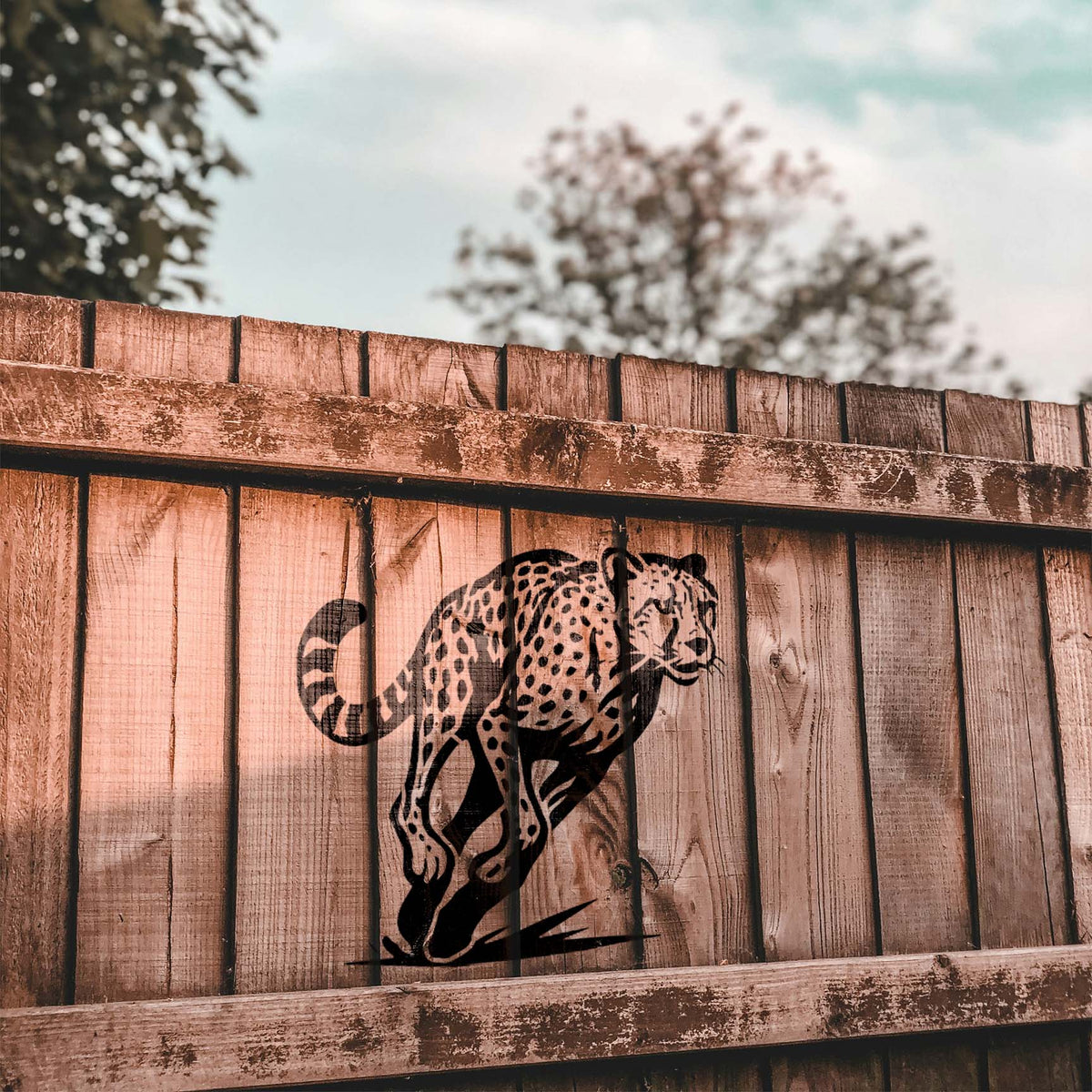 Leaping Cheetah Stencil painted in black on rustic wood fence