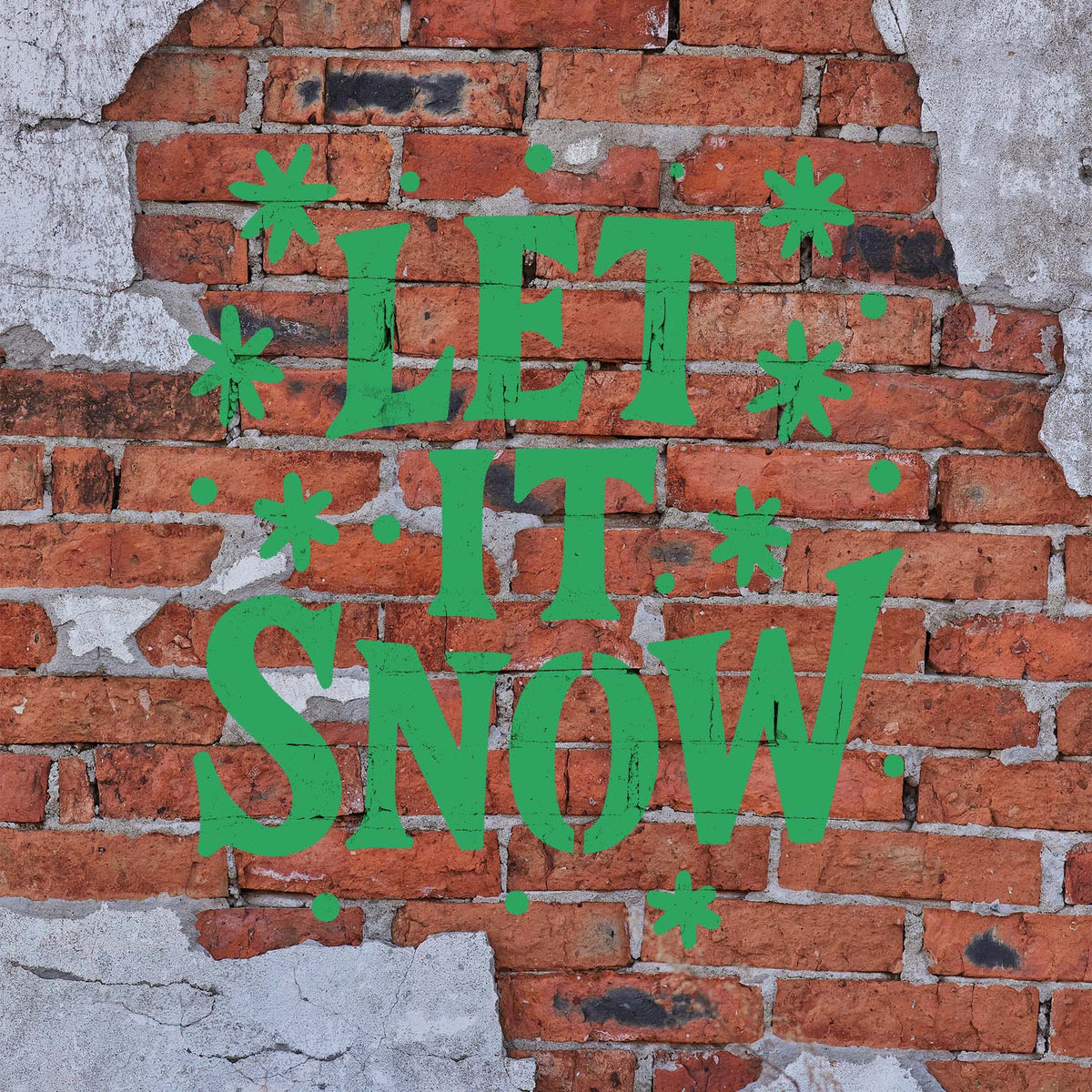 Let It Snow Hand Lettered Stencil stands out in green lettering across a weathered red brick wall.
