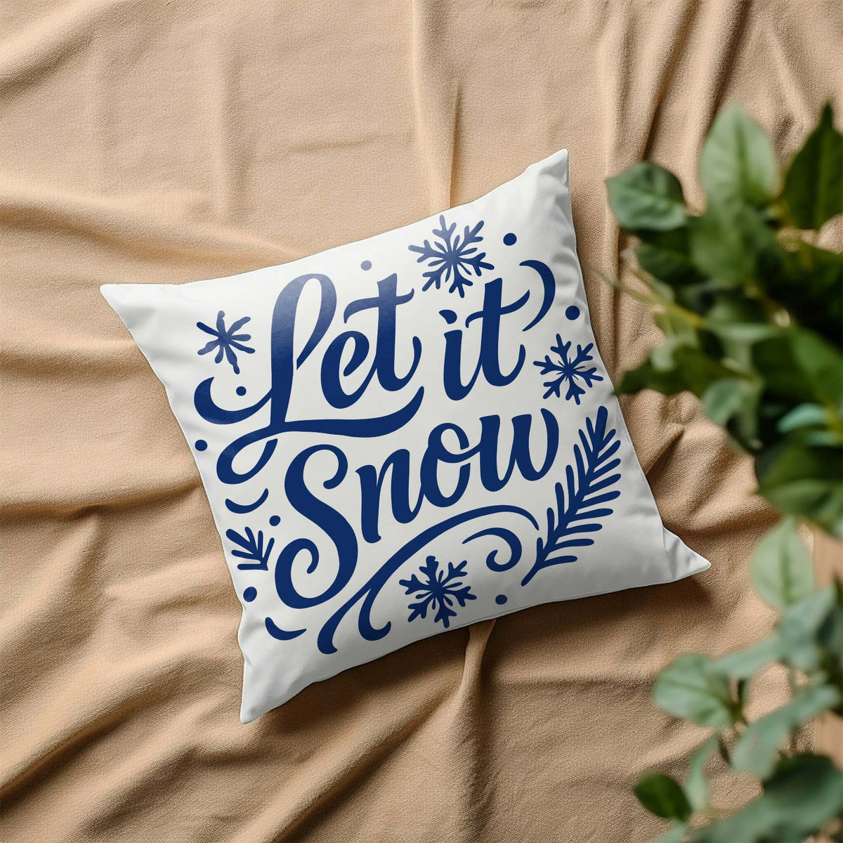 Blue Let It Snow Holiday Stencil decorates a white pillow with snowflakes and winter flourishes.