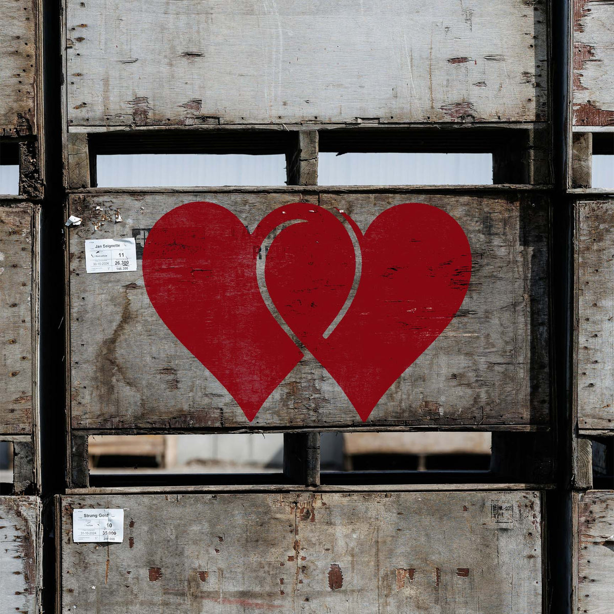 Linked Hearts Stencil painted in bold red across a weathered industrial wooden crate