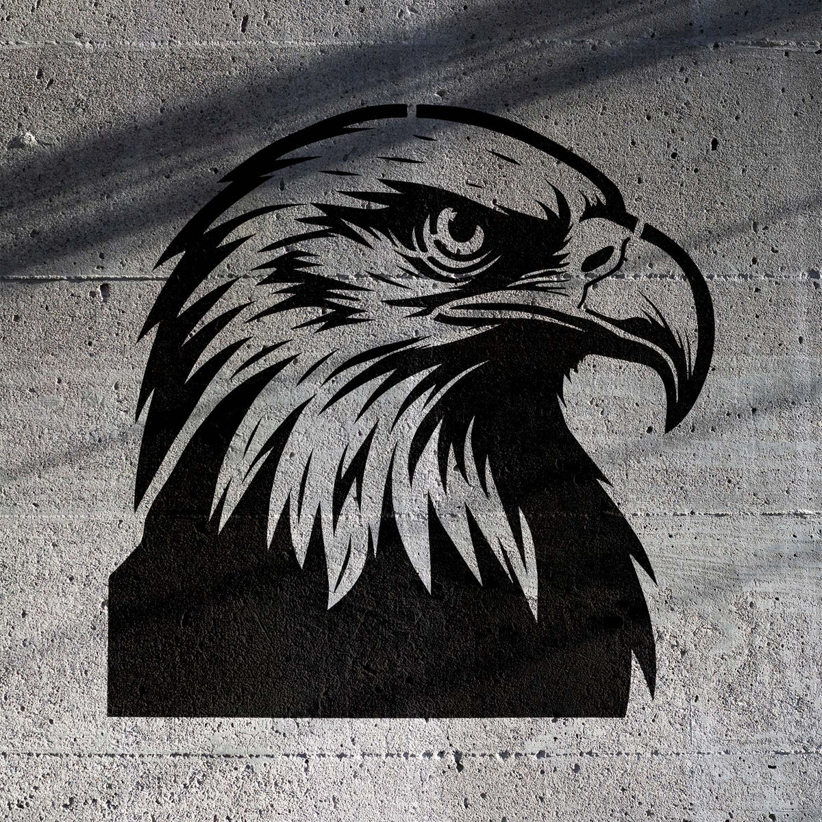 Fierce Majestic Bald Eagle Head Stencil stands out in black on rough concrete with piercing eyes and a hooked beak.