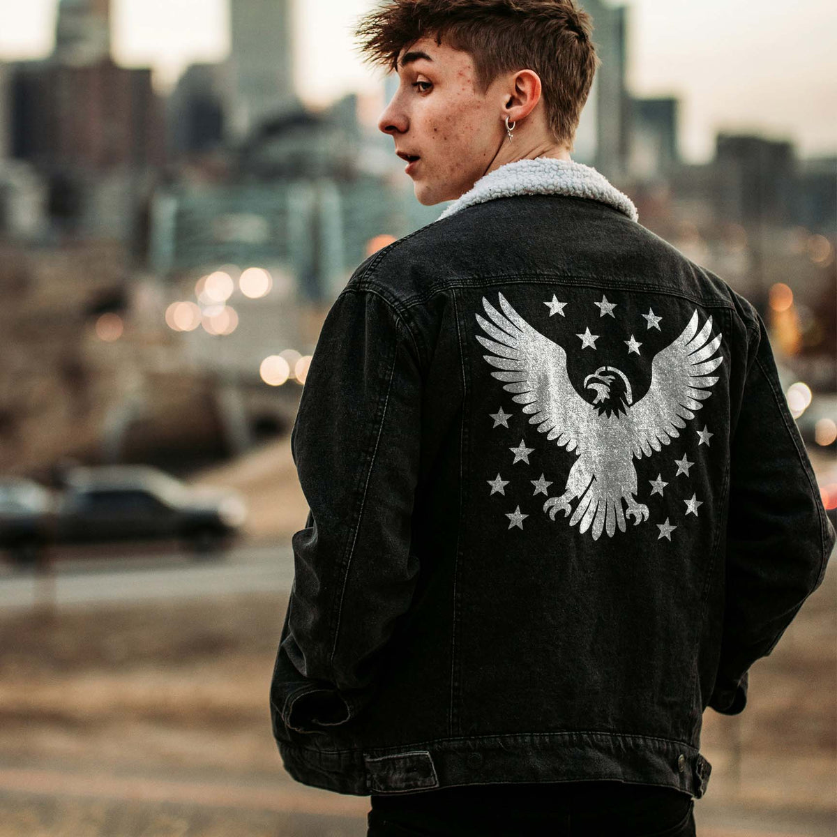 A black denim jacket features the Majestic Bald Eagle with Stars Stencil in silver-white with patriotic stars.