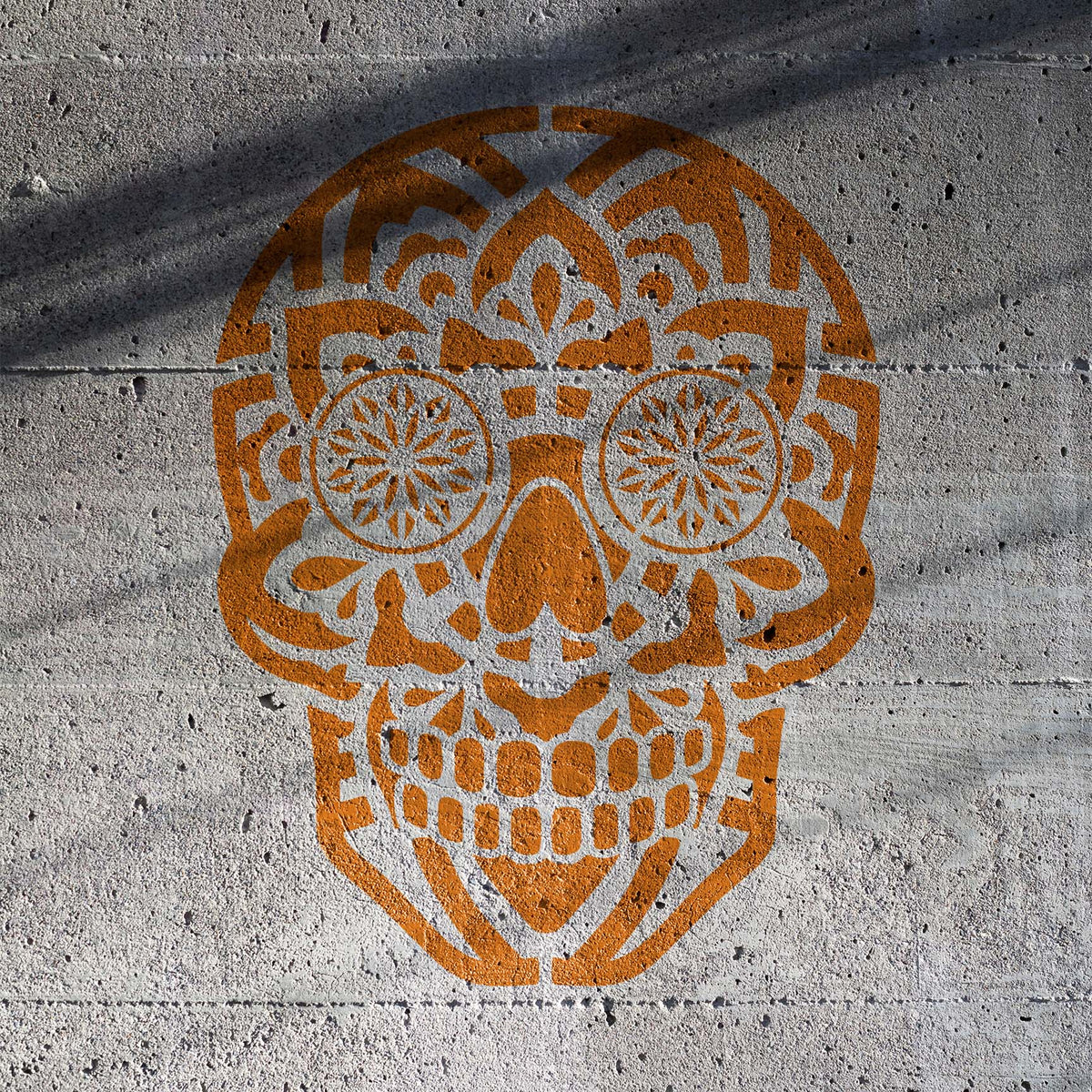 Bold Mandala Sugar Skull Stencil appears in burnt orange across a textured concrete wall