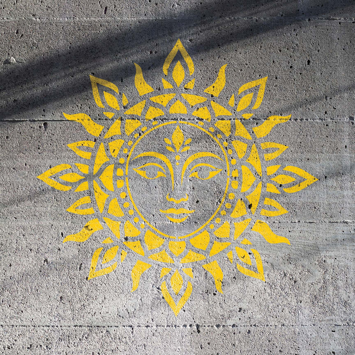 Mandala Sun Face Stencil painted yellow on a textured concrete wall