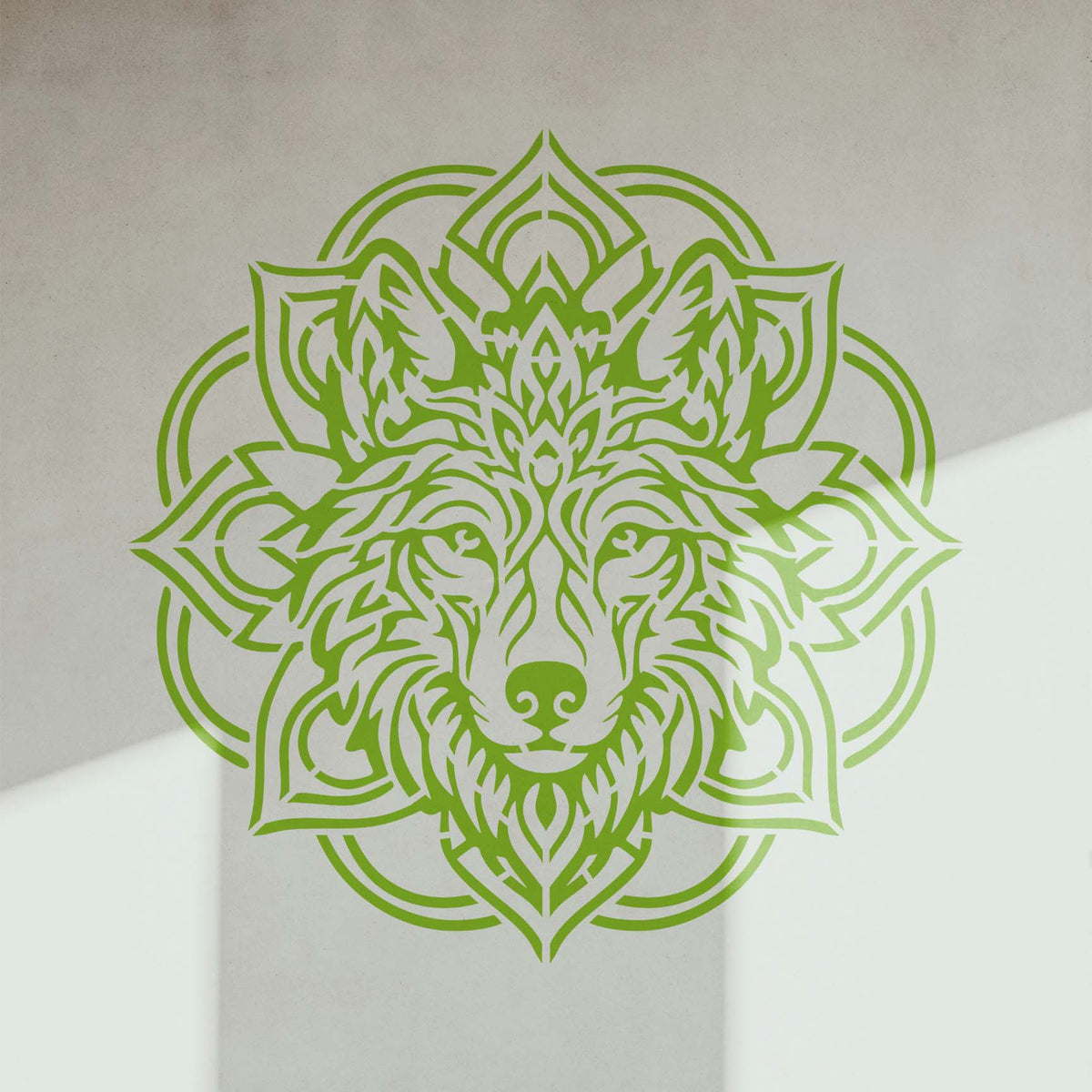 Sunlight crosses a green Mandala Wolf Head Stencil displayed on a clean white wall.