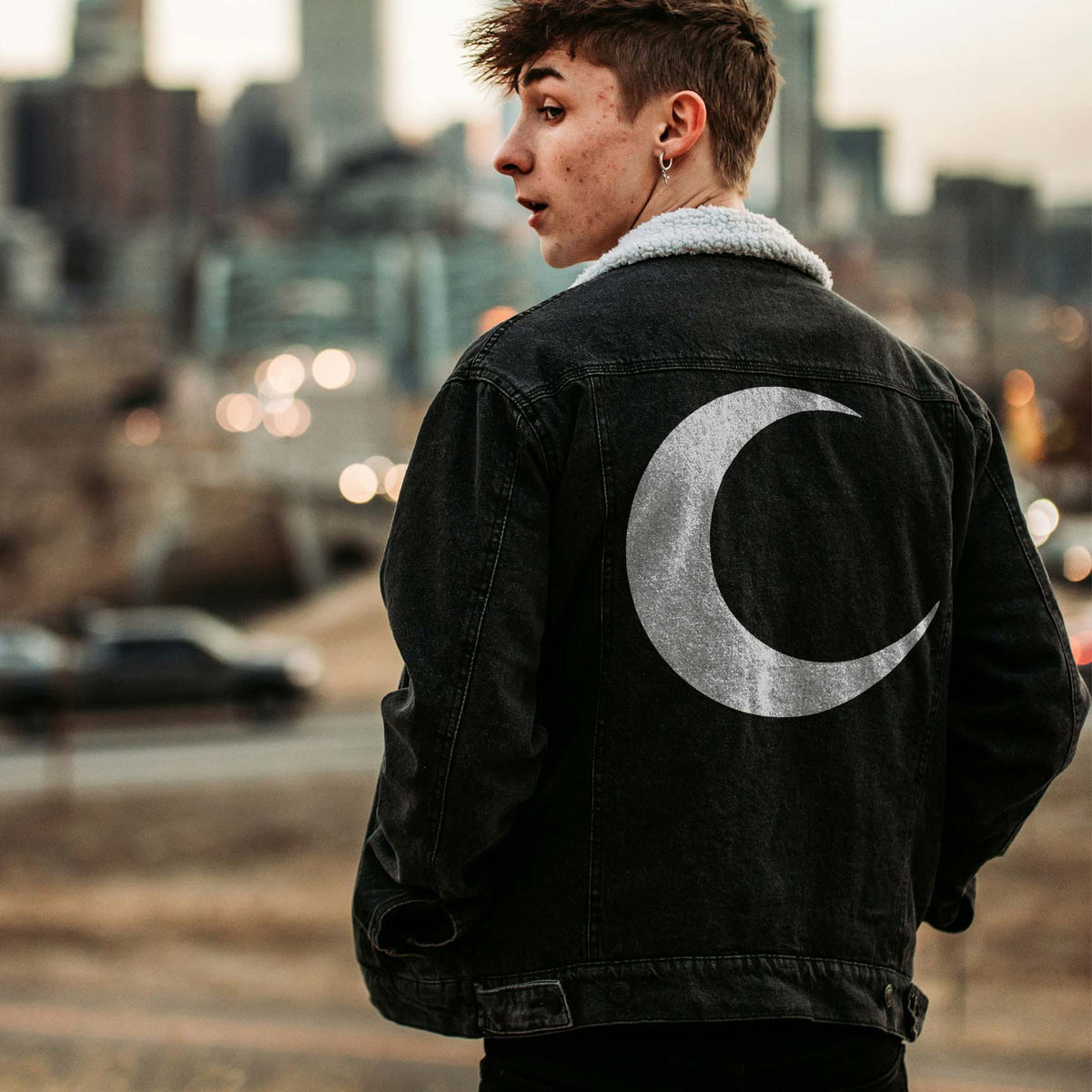 On a black denim jacket, the Minimalist Crescent Moon Stencil forms a striking silver lunar design.