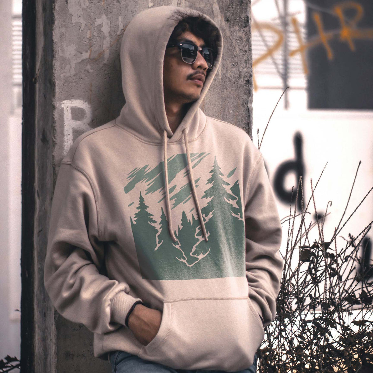 Misty Pine Forest stencil in muted green displayed on a beige hoodie