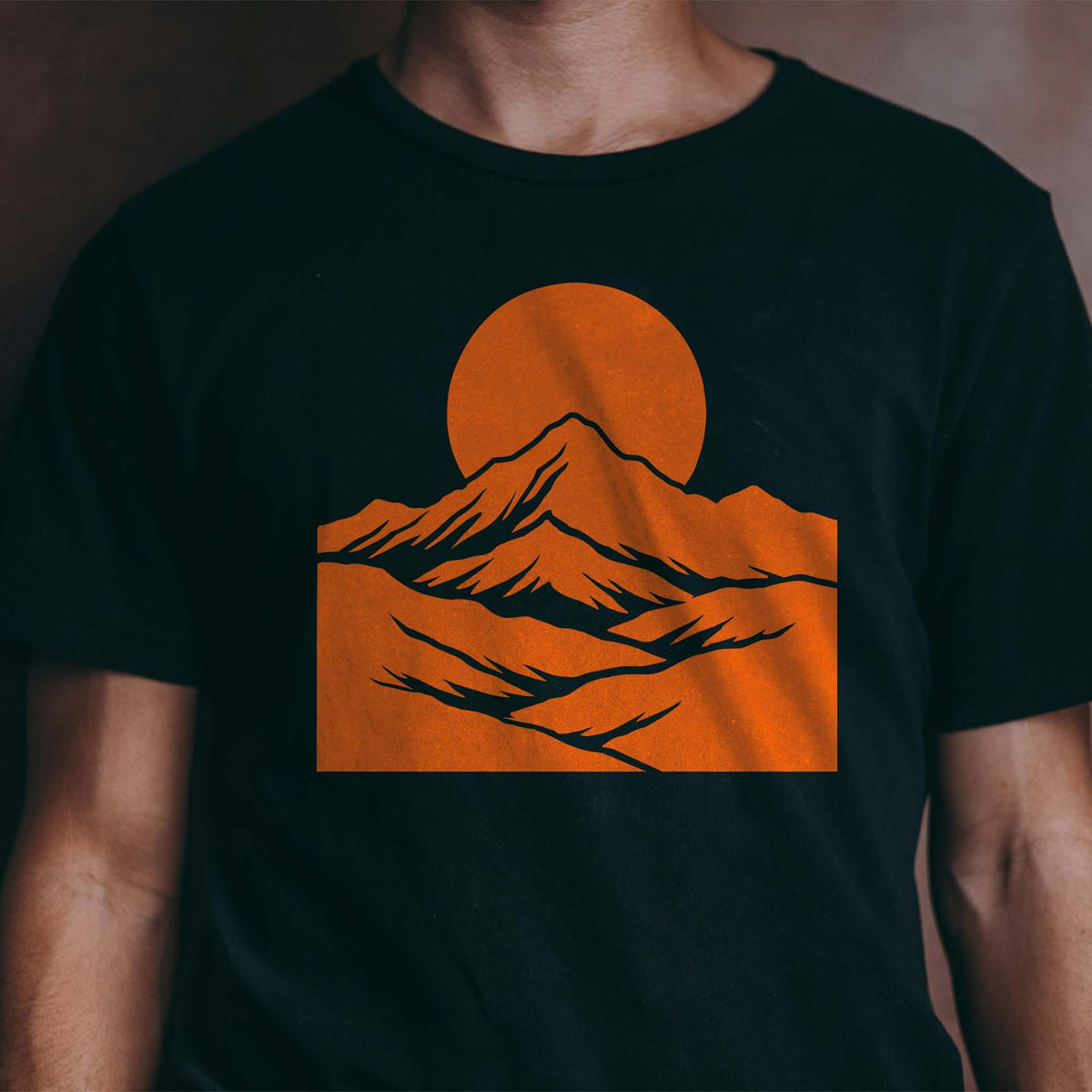 Mountain Moon Landscape Stencil painted in orange across a black T-shirt with layered peaks and moon