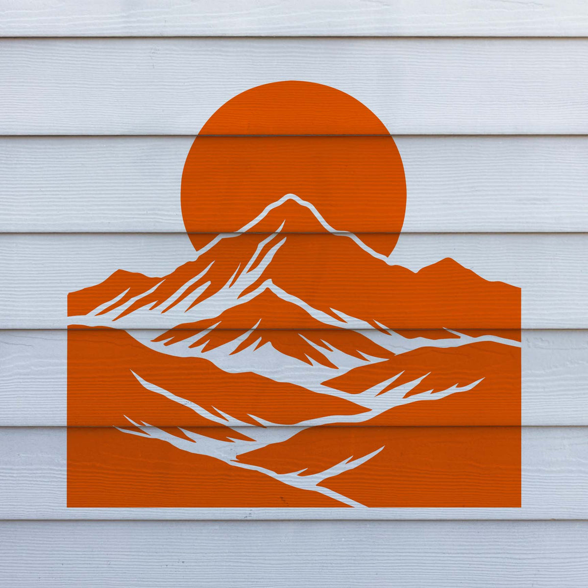 Bold Mountain Moon Landscape Stencil in orange on a white siding wall with layered mountain scenery