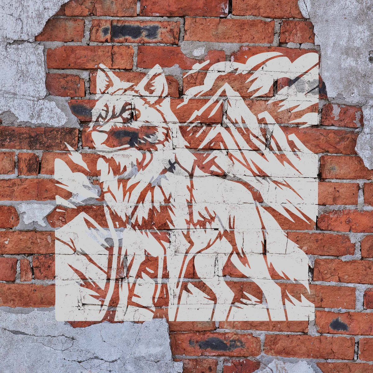 Weathered brick displays the Mountain Wolf Wilderness Stencil with a white wolf and mountain scene.