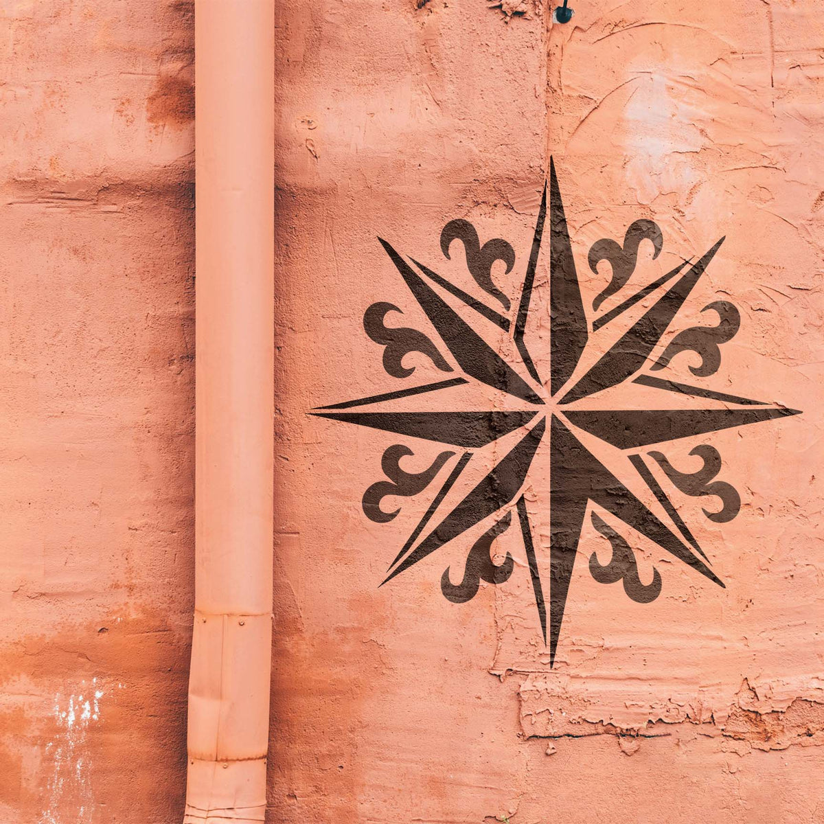 Weathered salmon wall showcases the Ornate Compass Star Stencil in a striking dark finish