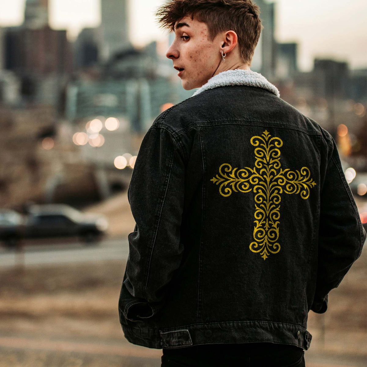 A black denim jacket features the Ornate Filigree Cross Stencil in a striking distressed gold finish