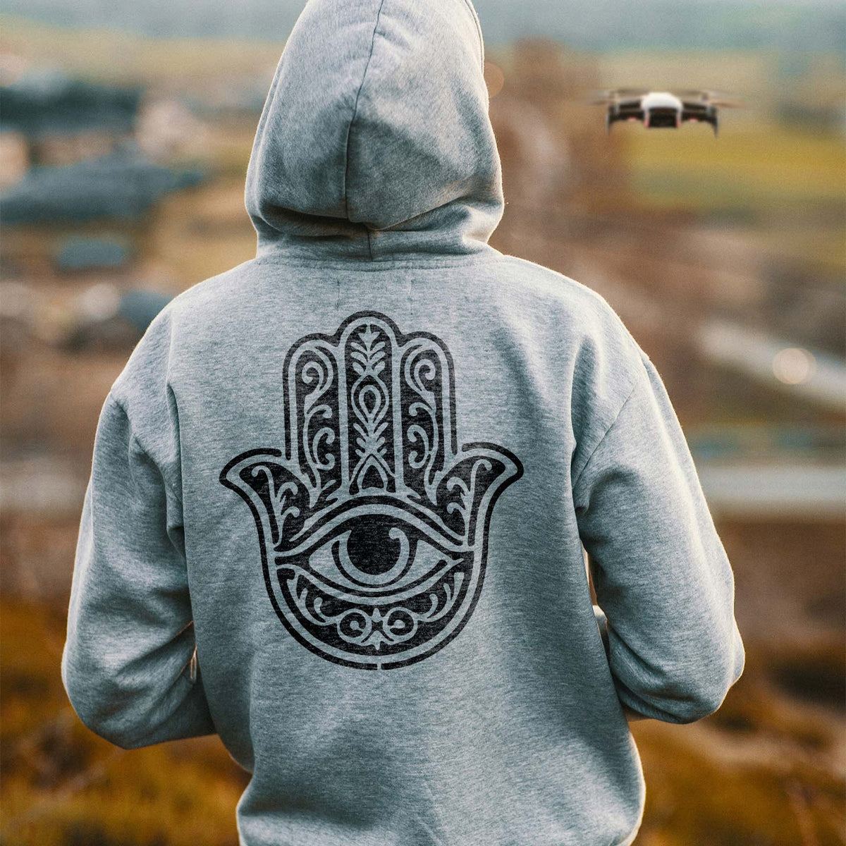 Gray hoodie displays the Ornate Hamsa Hand with Protective Eye Stencil in bold black detail