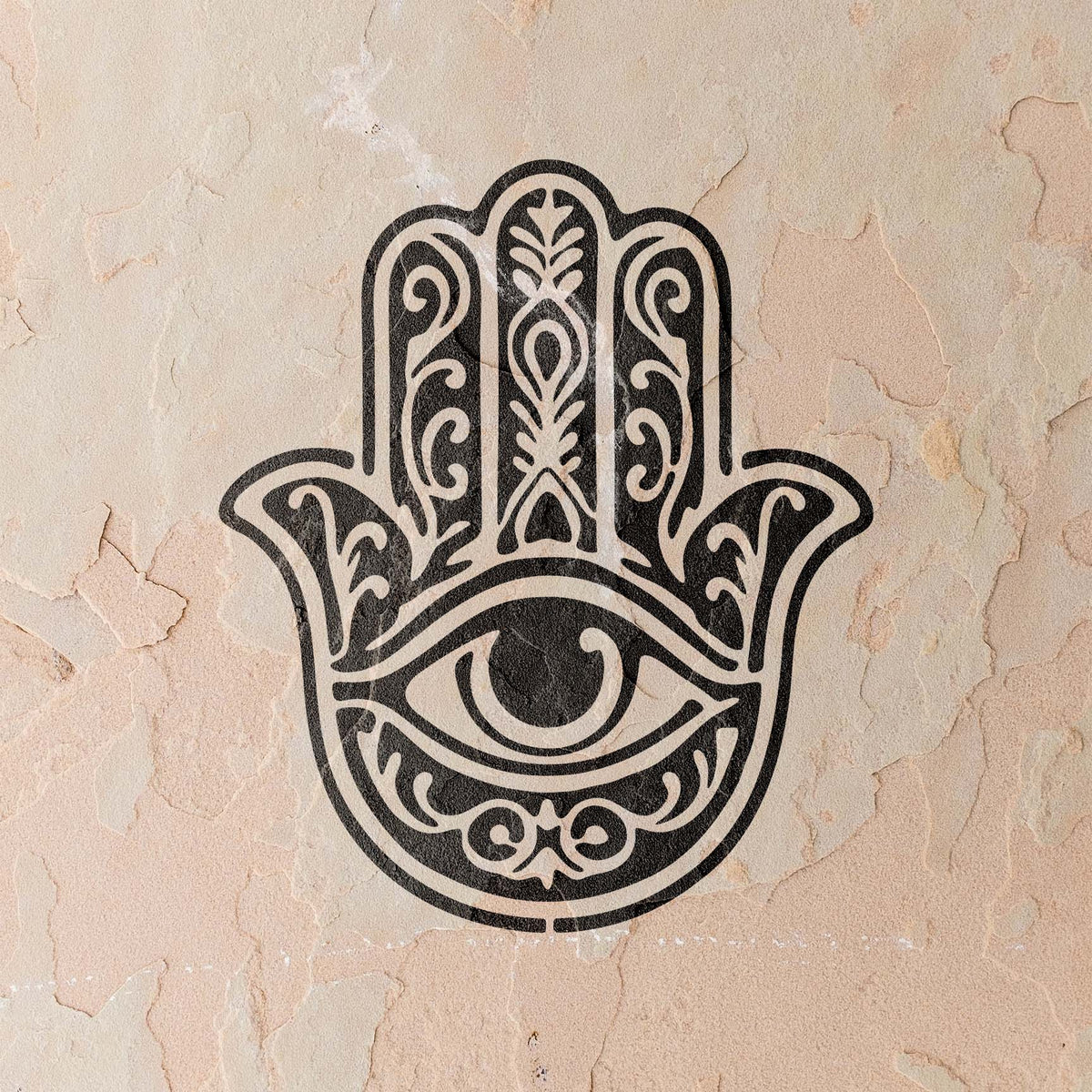 A textured plaster wall showcases the Ornate Hamsa Hand with Protective Eye Stencil in black