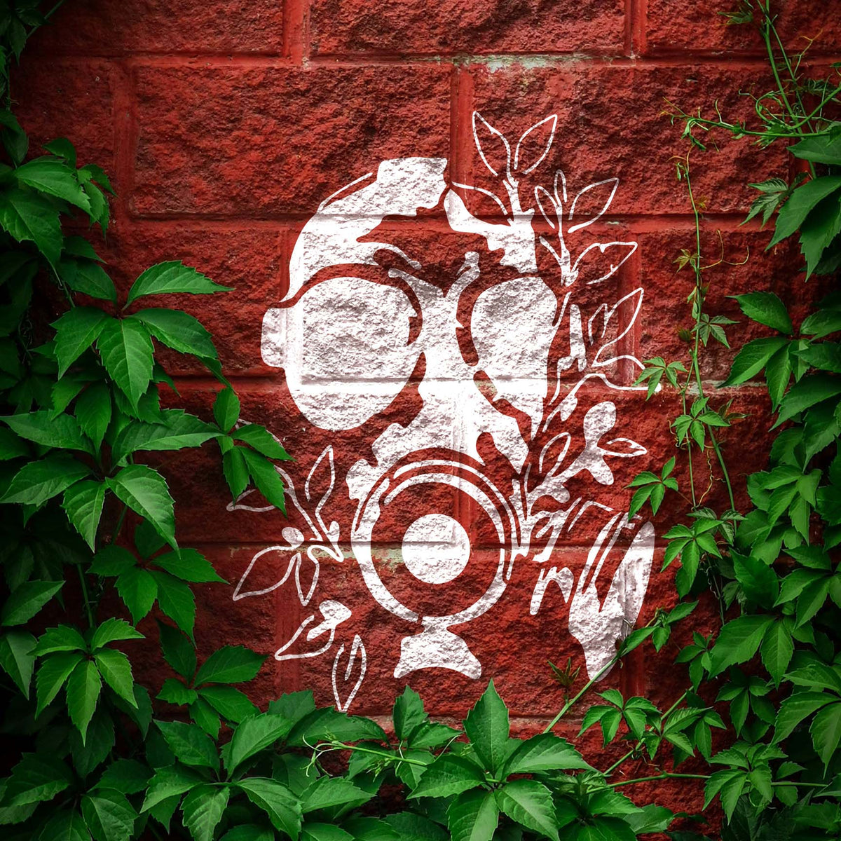 Framed by climbing ivy, the Overgrown Gas Mask Skull Stencil stands out in white on red brick