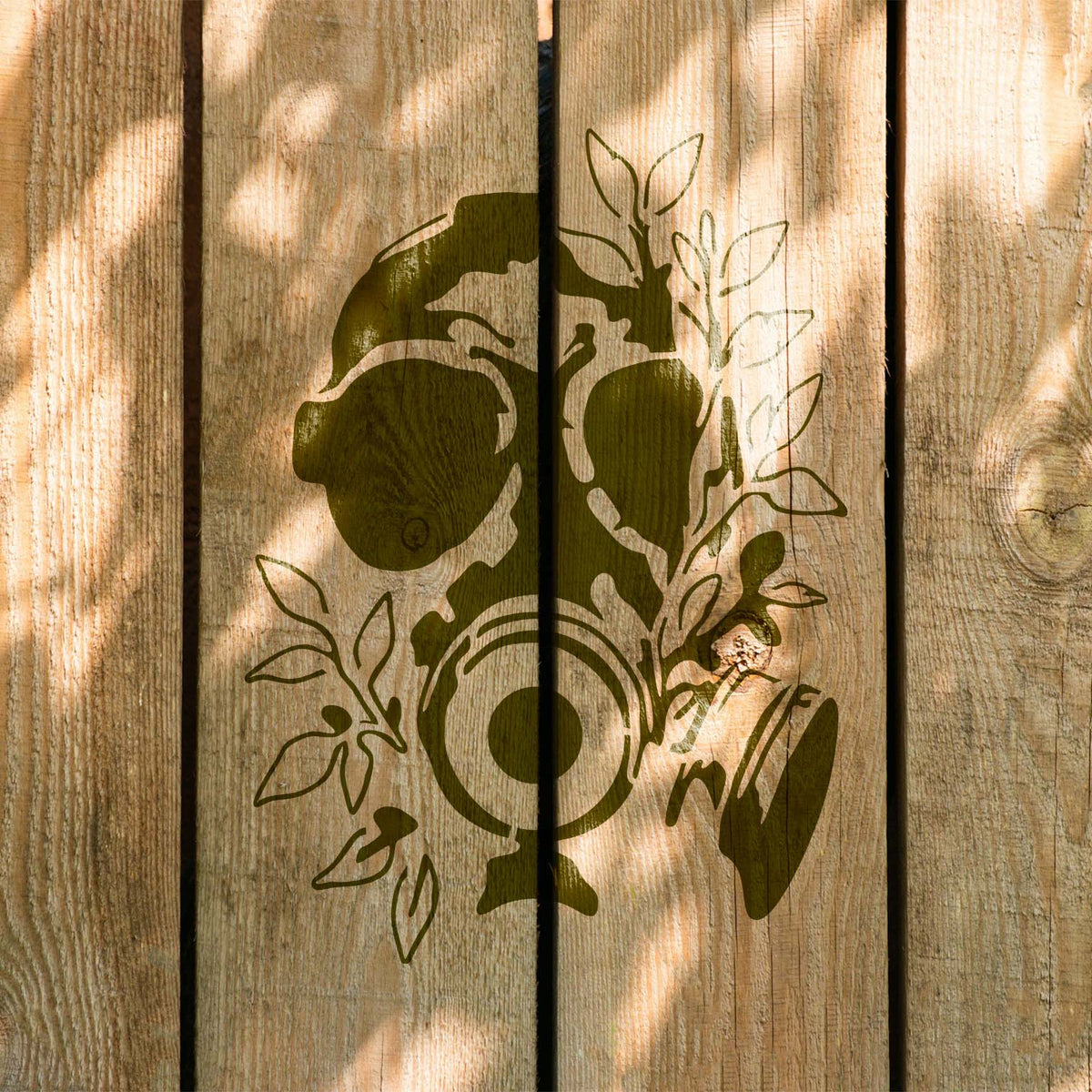 Leafy details weave around the Overgrown Gas Mask Skull Stencil painted across rustic wood planks