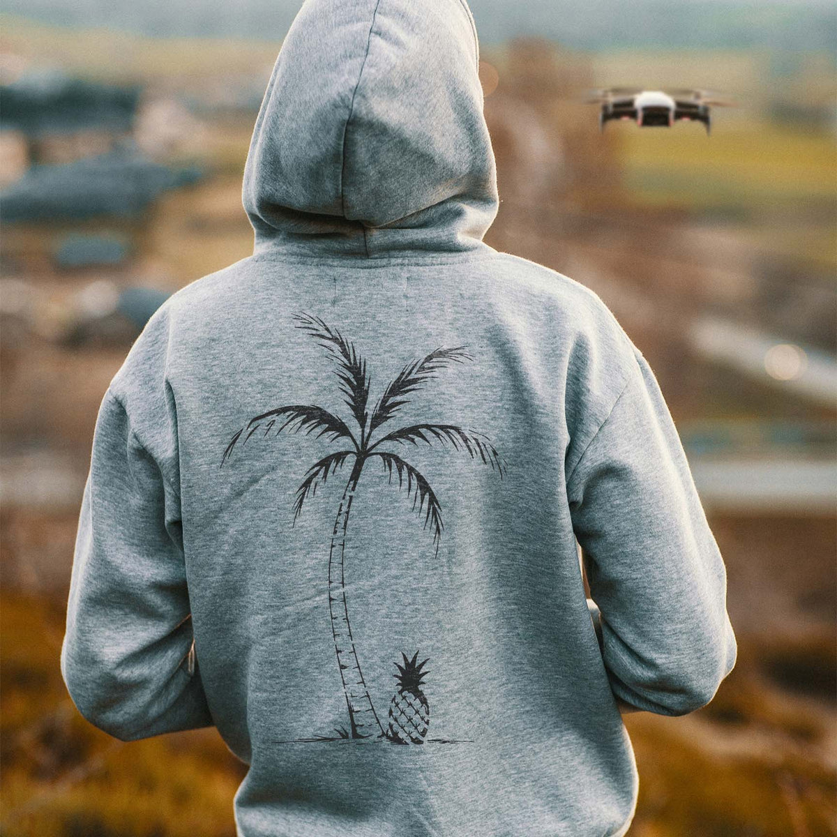 Tropical Palm & Pineapple Stencil featuring a tall palm and pineapple printed on the back of a gray hoodie