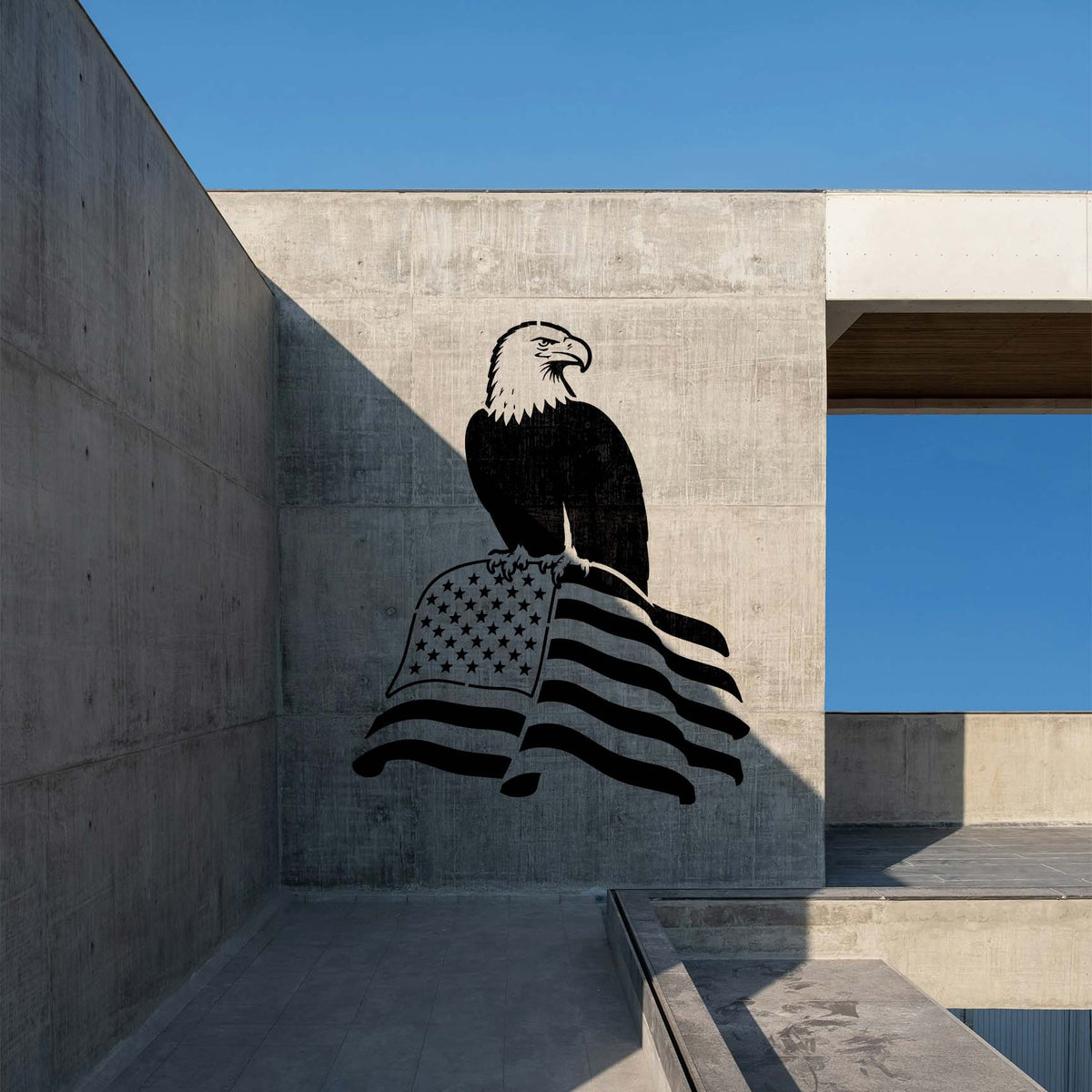 Bold Patriotic Eagle on American Flag Stencil decorates a concrete wall with a perched eagle and waving flag.