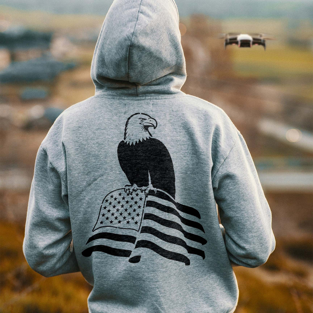 A gray hoodie features the Patriotic Eagle on American Flag Stencil in black across its back.