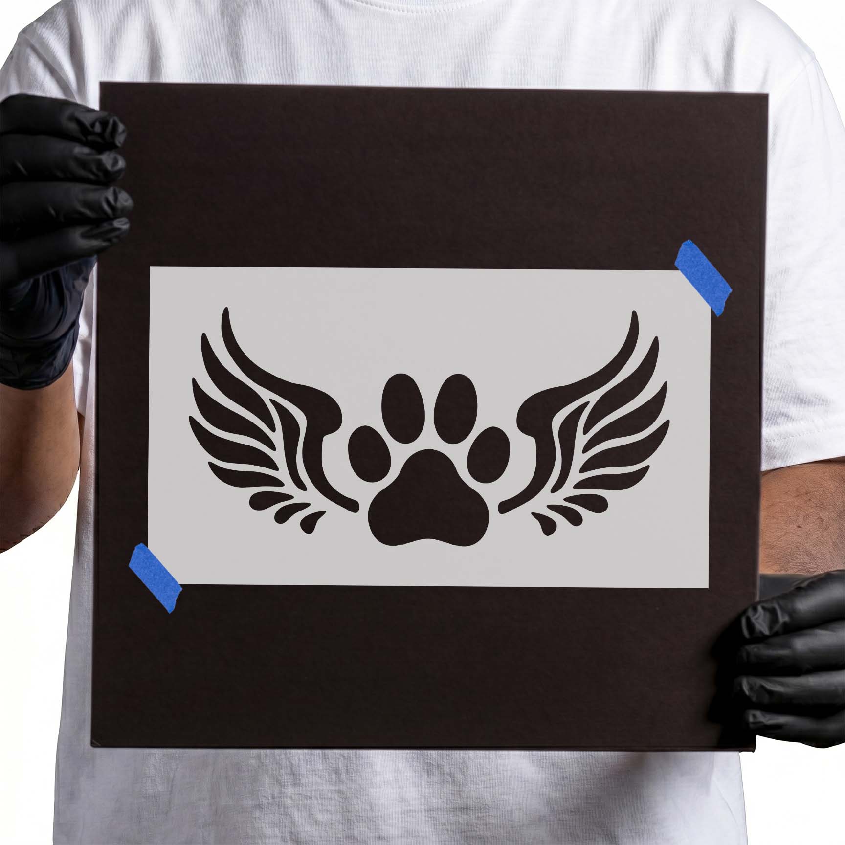 Person holding Angel Wings Paw Print Memorial Stencil taped to cardboard