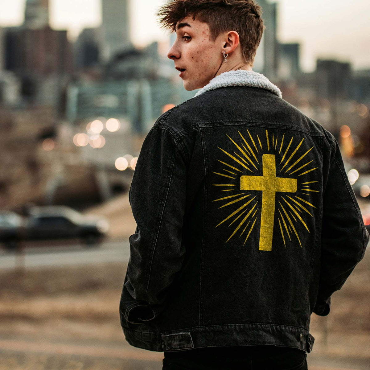 Radiant Cross Stencil glows in gold across the back of a black denim jacket with bold sunburst rays