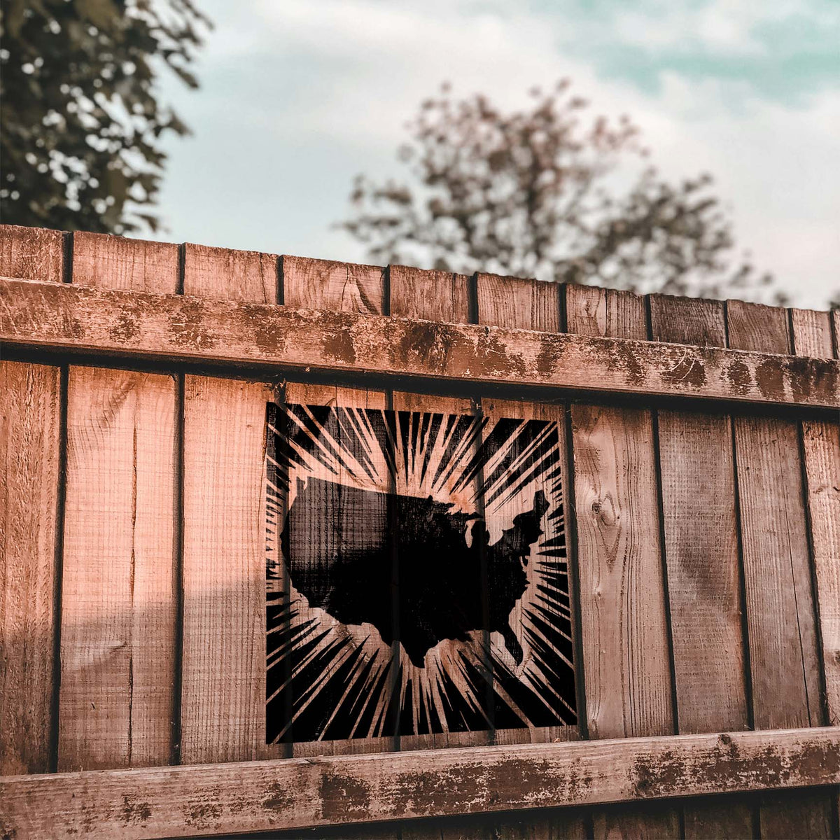 Bold Radiant USA Map Stencil decorates a rustic wood fence with striking radial lines