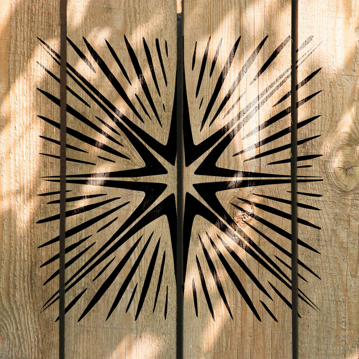 Radiating Eight-Point Star Burst Stencil spreads dramatic black rays across rustic wood planks