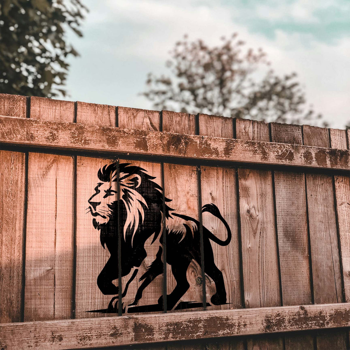 A bold black Regal Walking Lion Stencil strides across a weathered wooden fence.