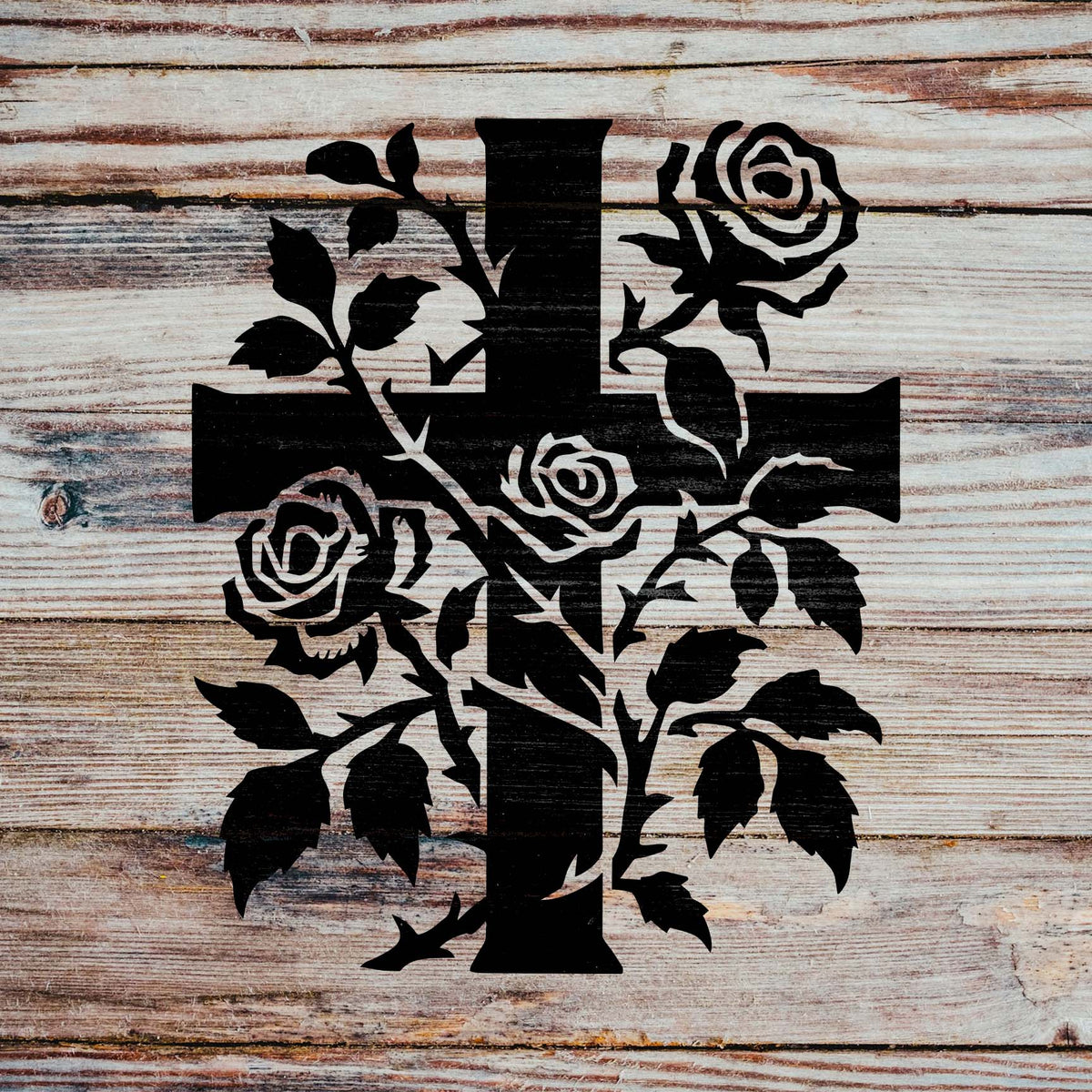 Rustic wood showcases the Rose Vine Cross Stencil with dark roses, leaves, and intertwining branches