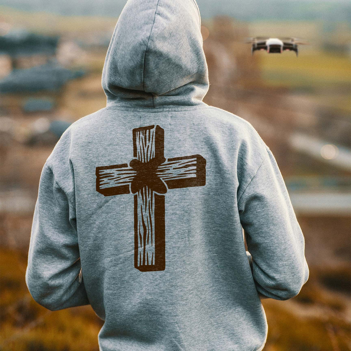 Back view of a gray hoodie featuring the Rustic Wooden Cross Stencil in a brown woodgrain print