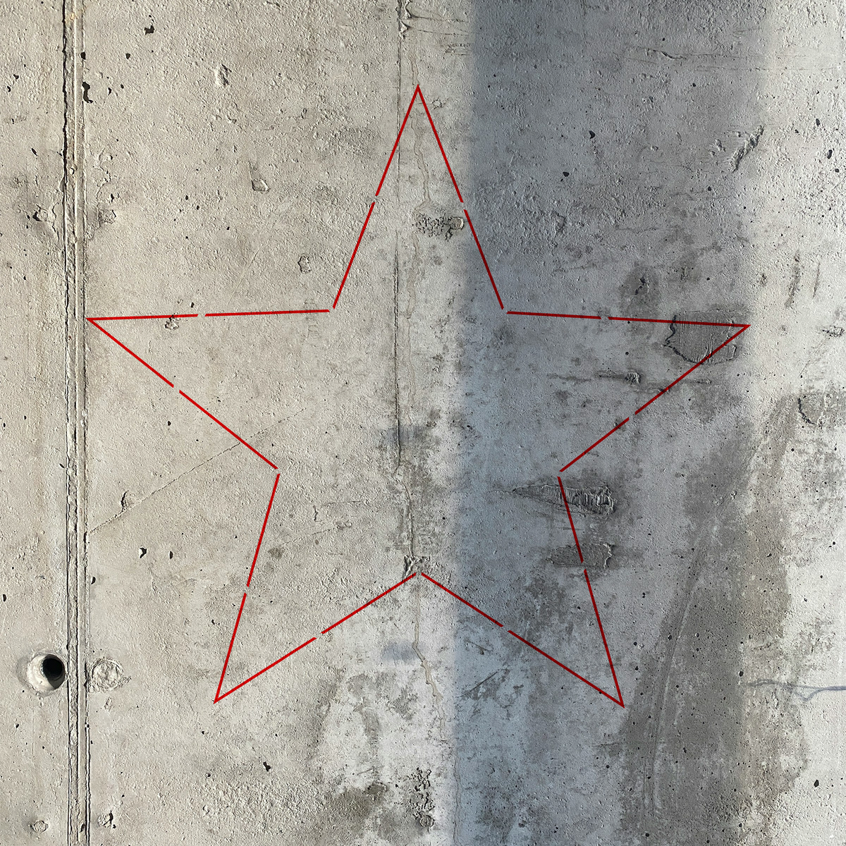 Simple Outline Star Stencil traced in red across a raw concrete wall with natural shadow