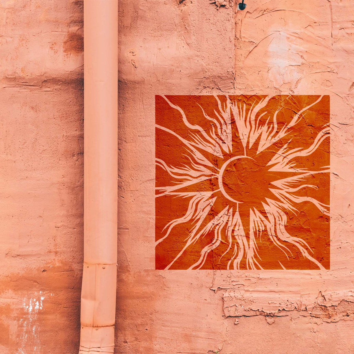 Against a salmon wall, Solar Eclipse Radiance Stencil forms a bold orange burst of solar rays
