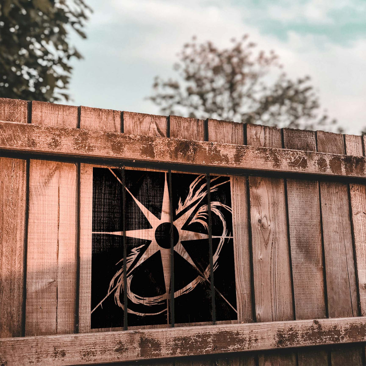 Rustic fence boards frame the Solar Flare Orbit Stencil in black with sweeping orbital curves