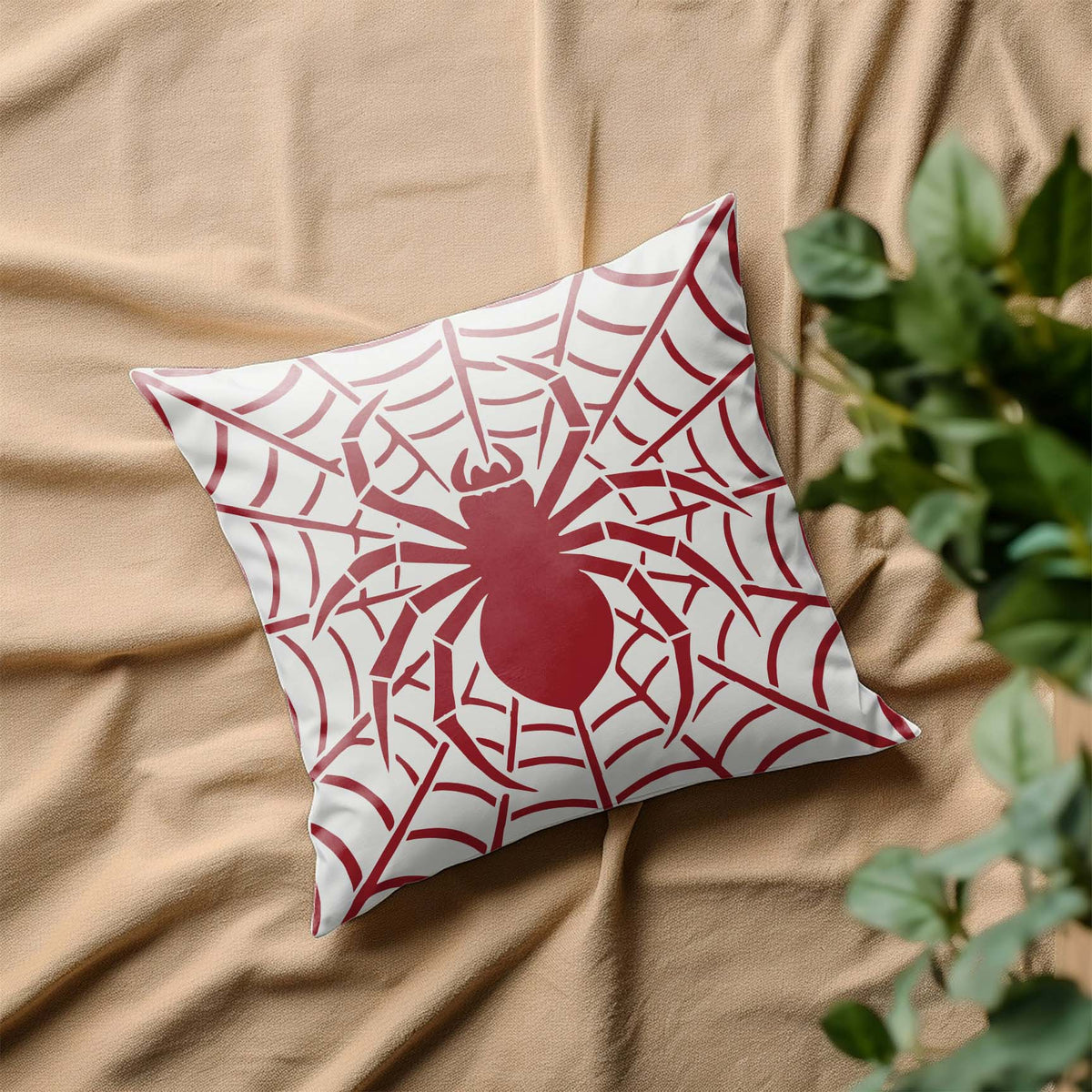 A red Spider Web Silhouette Stencil spreads its dramatic web and spider across a white pillow