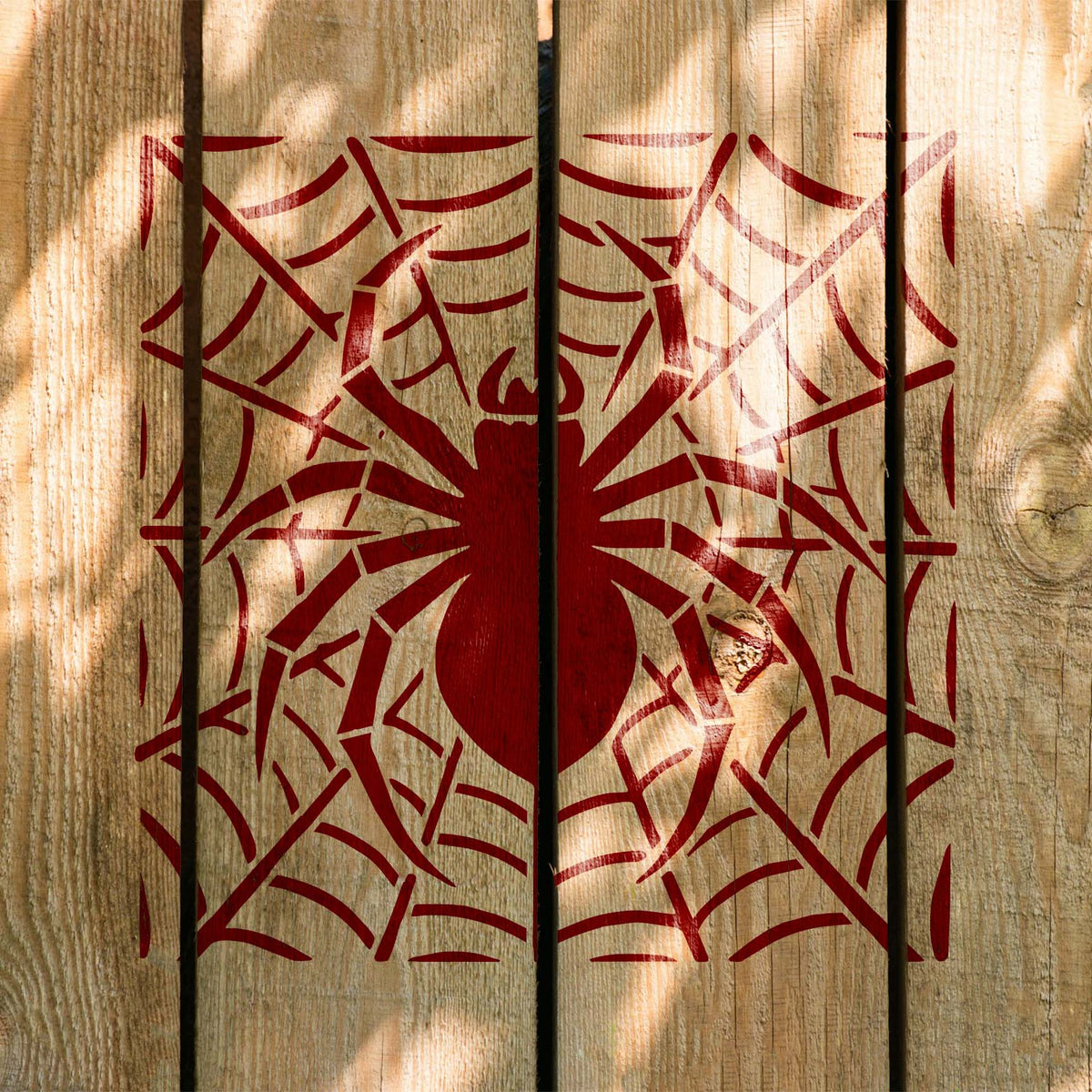 Deep red Spider Web Silhouette Stencil crawls across rustic wooden planks with a central spider